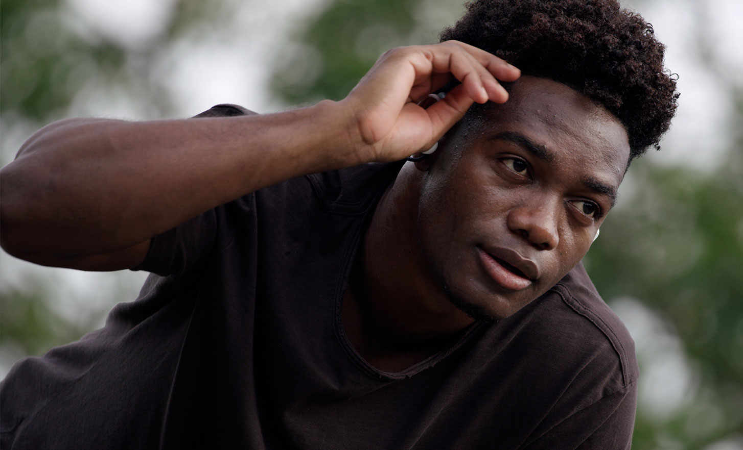 Imagen de un hombre al aire libre tocándose la frente con los audífonos Sony Float Run puestos